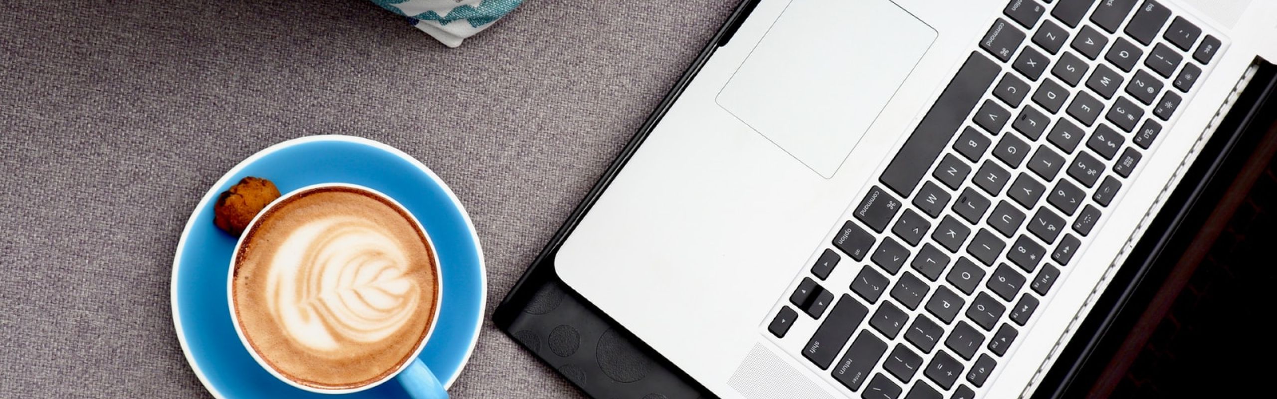 white ceramic mug with coffee beside macbook pro